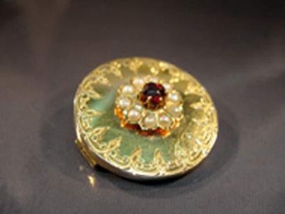 null BROCHE CIRCULAIRE EN OR JAUNE GUILLOCHÉ centrée d'un grenat entourage de demi-perles.
Vers...