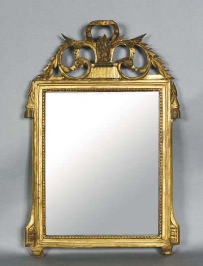 null Un miroir dans un encadrement à fronton découpé en bois et stuc doré, sculpté...