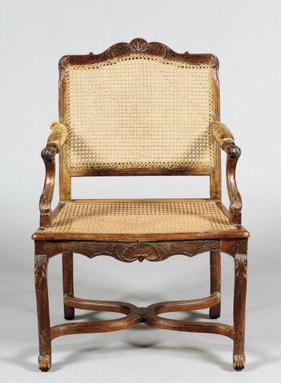 null Un fauteuil en bois naturel mouluré et sculpté à motifs de coquilles et feuillage...