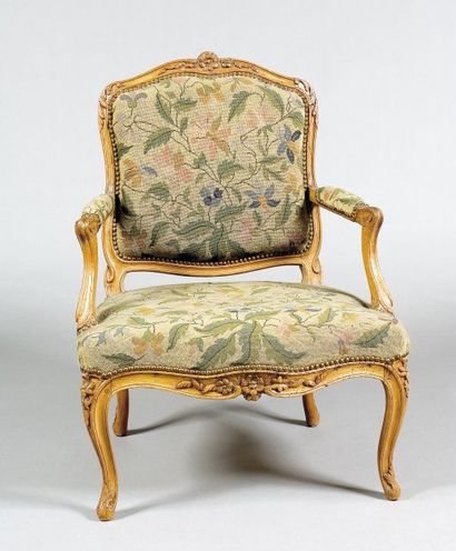 null Un fauteuil à dossier plat en bois naturel mouluré et sculpté de motifs de fleurettes....