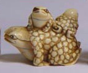 null Netsuké en ivoire à patine jaune représentant une grenouille, ses deux petits...
