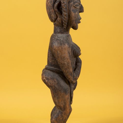 TCHAD 一件带有铜锈的木雕女人雕塑，表现为站立，一只手放在腰部的布上，一只手放在左胸下。
高度：67.5厘米。