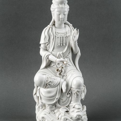 GUANYIN 白色的瓷器。在一个起伏的基础上。坐着的观音，左脚踩在龙头上，左手举起，右手拿着一个卷轴。背面盖有印章。中国，20世纪，高38厘米。