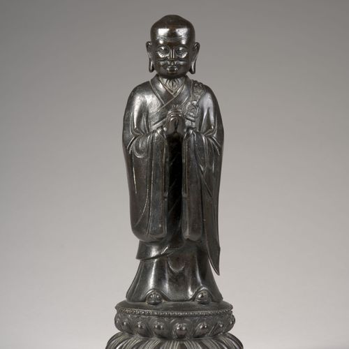 Null 青铜佛像，中国，明朝，17世纪

 
描绘了站在双层莲花形底座上，双手合十，身穿长长的僧袍，面容安详，眼睛半闭。

H.33.5厘米（13¼英寸）

&hellip;