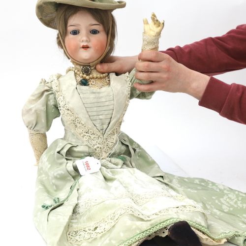 Null 一个阿曼德-马赛的娃娃模型390 11M。有一个瓷制的头，有蓝色虹膜的玻璃眼睛，完全穿着天鹅绒和蕾丝的薄荷绿裙子。高度：74厘米。
