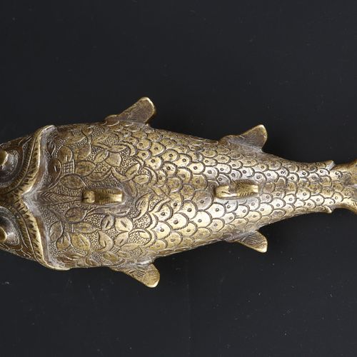 An Indian brass powder flask in the form of a fish. 一个印度铜制的鱼形火药瓶。印度，19世纪，刻有鱼鳞和花纹&hellip;