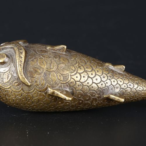 An Indian brass powder flask in the form of a fish. 一个印度铜制的鱼形火药瓶。印度，19世纪，刻有鱼鳞和花纹&hellip;