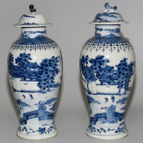 1 Paar Deckelvasen 中国，20世纪的瓷器。釉下蓝山水装饰，有亭台楼阁。有康熙款的标记。高37-37.5厘米。有木质底座。- 两者都已损坏。