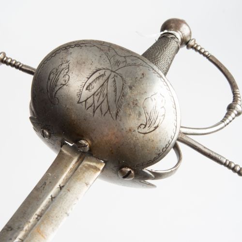 Glockendegen, Taza 铃铛剑，塔扎

西班牙，17世纪下半叶。 铁制剑柄，有一个沼泽状的球状鞍座，护手上也有装饰。原本光滑的铃铛上的花纹雕刻在第&hellip;