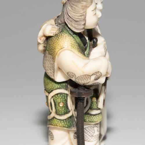 NETSUKE 网状物

日本，明治时期。象牙，部分上色，镶嵌有柴山风格的珍珠母。签名的高安。描绘的是一对夫妇，其中一名男子拄着一把武士刀。高5,5厘米。