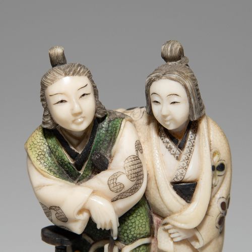 NETSUKE 网状物

日本，明治时期。象牙，部分上色，镶嵌有柴山风格的珍珠母。签名的高安。描绘的是一对夫妇，其中一名男子拄着一把武士刀。高5,5厘米。