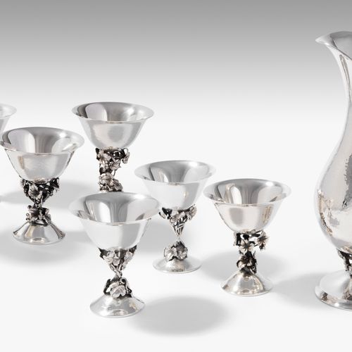 Weinkanne und 7 Fussbecher 酒壶和7脚杯

巴塞罗那，1950年代。银色，锤击。标记为阿蒙戈尔。圆底，轴上有藤蔓和葡萄卷须，上面是芭蕾&hellip;