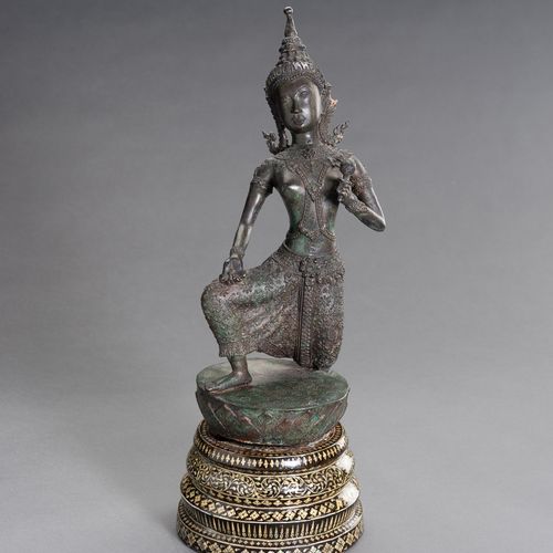 A BRONZE FIGURE OF A DANCING APSARA 一尊跳舞的阿帕拉铜像
柬埔寨，1920年。这尊铜像以生动的姿态跪在莲花苞上，身穿桑普，戴&hellip;