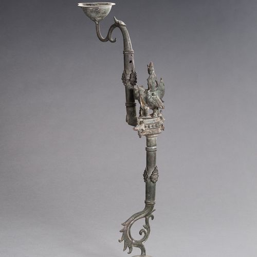 AN UNUSUAL BRONZE OIL LAMP 一个不寻常的青铜油灯
东南亚，17-19世纪。由三部分组成，从一个弯曲的脚升起，铸有几个装饰性的图案，中央&hellip;