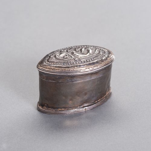 AN OVAL-SHAPED SILVER MEDICINE BOX 椭圆形银质药箱
缅甸/缅甸，19世纪。椭圆形的银盒盖上有精美的浮雕图案。

状况。 有凹痕&hellip;