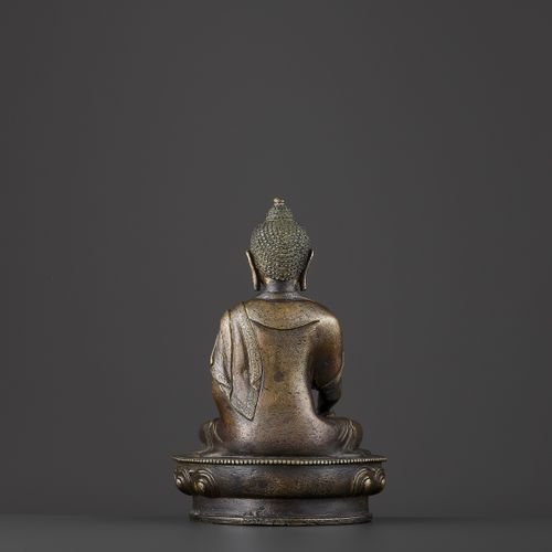 A BRONZE BUDDHA SHAKYMUNI 一件青铜佛像释迦牟尼
中国，19世纪末。菩萨坐于珠饰莲花座上，身着精细雕刻的长袍，长袍垂于肩上，褶皱落于手臂&hellip;