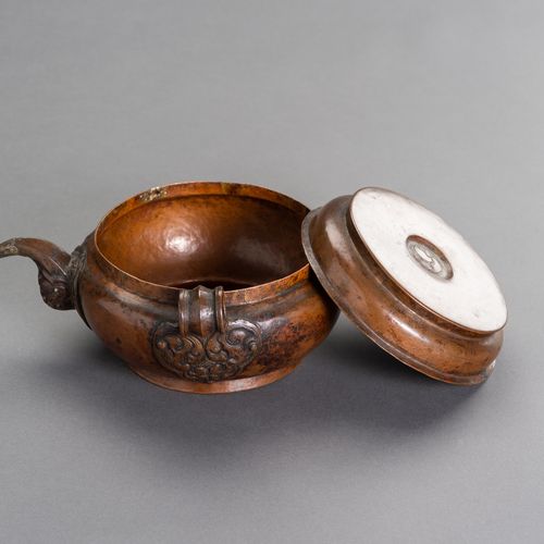 A RITUAL TIBETAN COPPER WATERPOT 祭祀用的西藏铜水壶
西藏，19世纪。小型祭祀铜水壶有平盖，卷轴式壶嘴和环形把手。盖子中间有刻印&hellip;