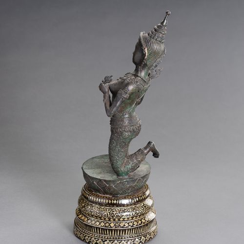 A BRONZE FIGURE OF A DANCING APSARA 一尊跳舞的阿帕拉铜像
柬埔寨，1920年。这尊铜像以生动的姿态跪在莲花苞上，身穿桑普，戴&hellip;