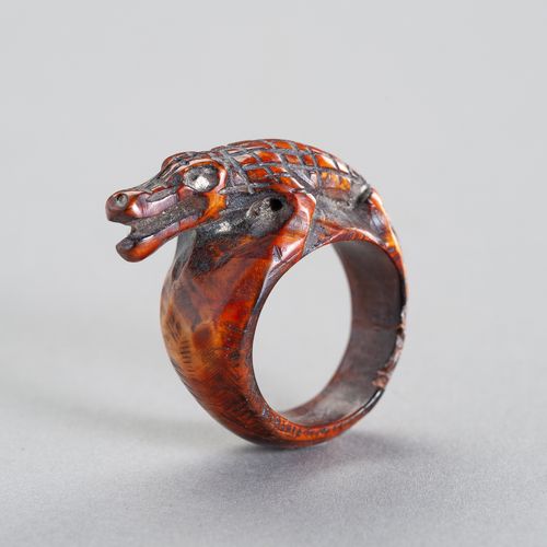 A TRIBAL `COCODRILE´ IVORY RING 一个部落的 "鳄鱼 "象牙戒指
东南亚，19世纪或更早。这个雕刻着鳄鱼的民族戒指显示出美丽的深琥&hellip;