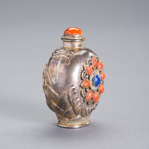 AN EMBELLISHED SILVER SNUFF BOTTLE 一个有纹饰的银质鼻烟壶
中国，19世纪。一面是高浮雕的龙，另一面是嵌有珊瑚、青金石和丝线的&hellip;