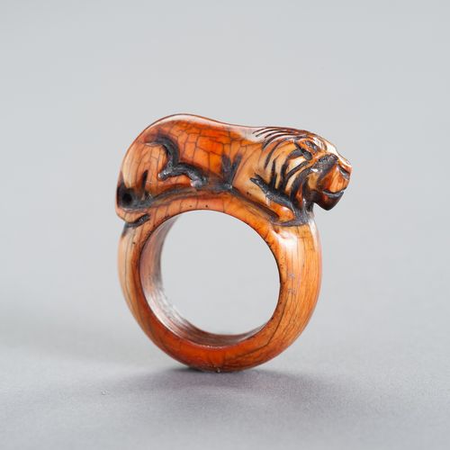 A TRIBAL ´TIGER´ IVORY RING 一个部落的 "老虎 "象牙戒指
东南亚，19世纪或更早。这个民族的戒指雕刻着一只卧虎，显示出美丽的深琥珀&hellip;