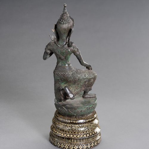 A BRONZE FIGURE OF A DANCING APSARA 一尊跳舞的阿帕拉铜像
柬埔寨，1920年。这尊铜像以生动的姿态跪在莲花苞上，身穿桑普，戴&hellip;