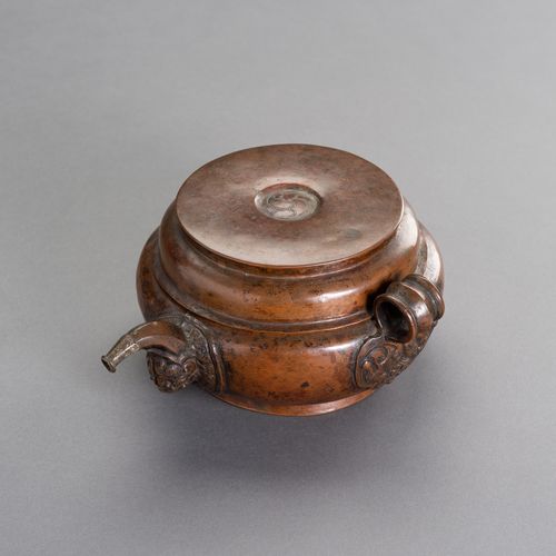 A RITUAL TIBETAN COPPER WATERPOT 祭祀用的西藏铜水壶
西藏，19世纪。小型祭祀铜水壶有平盖，卷轴式壶嘴和环形把手。盖子中间有刻印&hellip;