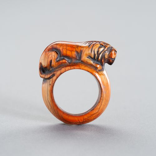 A TRIBAL ´TIGER´ IVORY RING 一个部落的 "老虎 "象牙戒指
东南亚，19世纪或更早。这个民族的戒指雕刻着一只卧虎，显示出美丽的深琥珀&hellip;