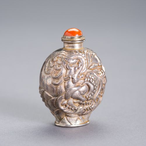 AN EMBELLISHED SILVER SNUFF BOTTLE 一个有纹饰的银质鼻烟壶
中国，19世纪。一面是高浮雕的龙，另一面是嵌有珊瑚、青金石和丝线的&hellip;