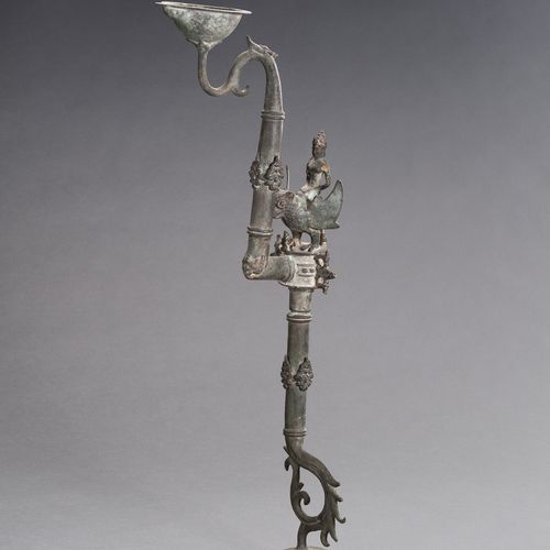 AN UNUSUAL BRONZE OIL LAMP 一个不寻常的青铜油灯
东南亚，17-19世纪。由三部分组成，从一个弯曲的脚升起，铸有几个装饰性的图案，中央&hellip;