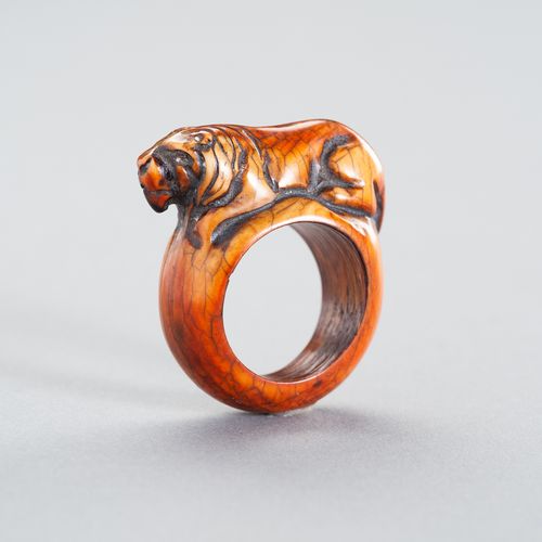 A TRIBAL ´TIGER´ IVORY RING 一个部落的 "老虎 "象牙戒指
东南亚，19世纪或更早。这个民族的戒指雕刻着一只卧虎，显示出美丽的深琥珀&hellip;