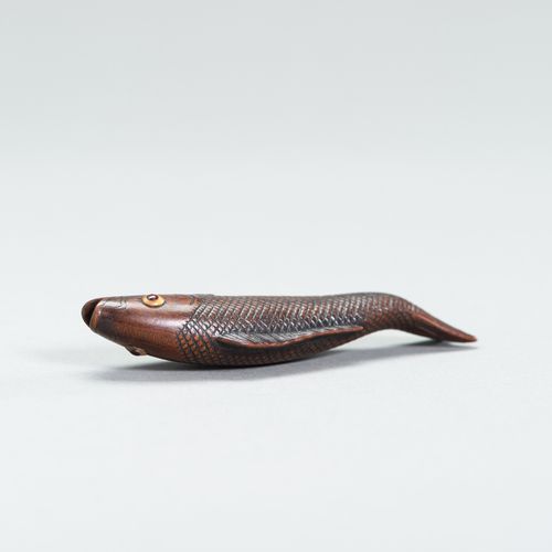 A LARGE WOOD FISH NETSUKE 大型木制鱼网袜
日本，19世纪

描绘了一条游泳的鱼，鱼鳞和鱼鳍都雕刻得很精细，眼睛是用黄色和红色的角
镶嵌&hellip;