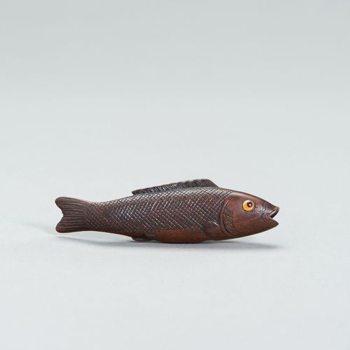 A LARGE WOOD FISH NETSUKE 大型木制鱼网袜
日本，19世纪

描绘了一条游泳的鱼，鱼鳞和鱼鳍都雕刻得很精细，眼睛是用黄色和红色的角
镶嵌&hellip;