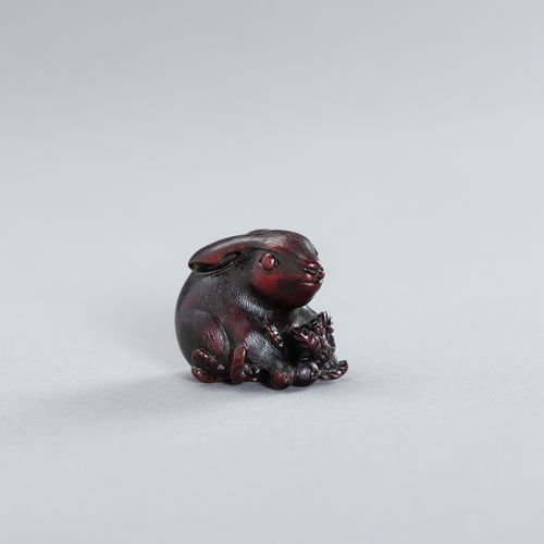 A WOOD NETSUKE OF A HARE WITH BIWA FRUIT 
日本明治时期(1868-1912)

兔子坐着，两只爪子放在水果上，它的长耳&hellip;