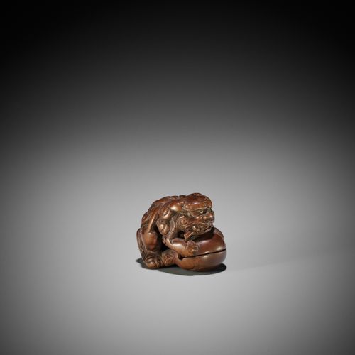 AN EARLY WOOD NETSUKE OF A SHISHI ON A MOKUGYO AN EARLY WOOD NETSUKE OF A SHISHI&hellip;