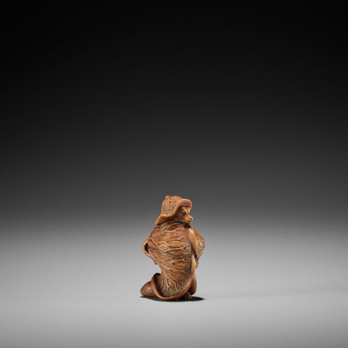 A TANBA SCHOOL WOOD NETSUKE OF A TANUKI WRAPPED IN LOTUS LEAVES 
UN NETSUKE IN L&hellip;