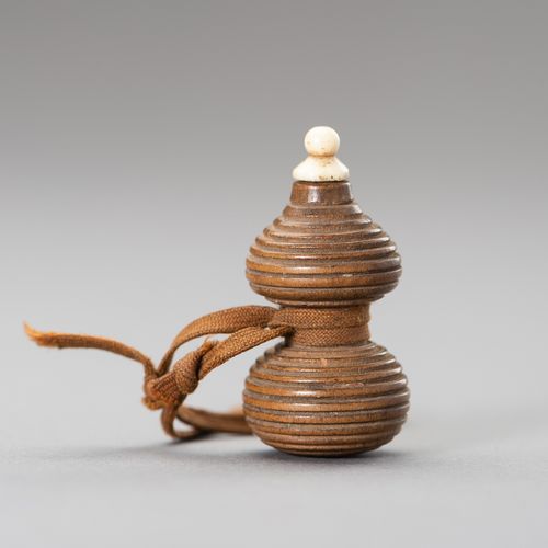 A HYOTAN SHAPE WOOD NETSUKE 一个HYOTAN形状的木制网罩
日本，19世纪

这个网罩是由木头雕刻而成的，用编织绳包裹，上面有一个骨&hellip;