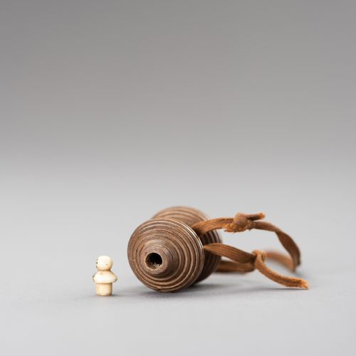 A HYOTAN SHAPE WOOD NETSUKE 一个HYOTAN形状的木制网罩
日本，19世纪

这个网罩是由木头雕刻而成的，用编织绳包裹，上面有一个骨&hellip;