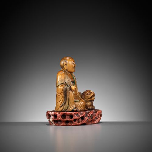 A SOAPSTONE FIGURE OF A LUOHAN WITH A BUDDHIST LION, 18TH CENTURY FIGURA DE JABÓ&hellip;