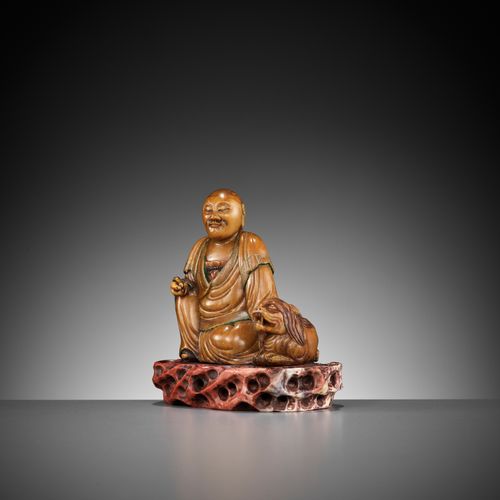 A SOAPSTONE FIGURE OF A LUOHAN WITH A BUDDHIST LION, 18TH CENTURY SEIFSTEINFIGUR&hellip;