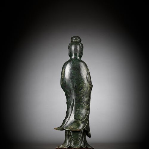 A LARGE AND MASSIVE SPINACH-GREEN KHOTAN JADE FIGURE OF GUANYIN, PROBABLY TAKEN &hellip;