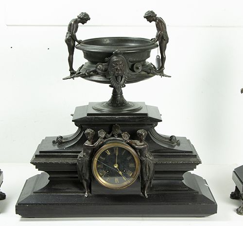 Null 钟 - 三件套时钟，包括：黑色大理石表壳的时钟，两侧有两个打手鼓的女人，冠以一个瓮形的花园，内有盆子，黑色珐琅表盘上有罗马数字和两个罗马女人的复合雕像&hellip;