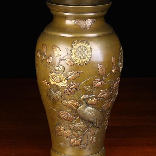 Null 一个精致的日本青铜花瓶，呈上升状，上面有丰富的镶嵌和贴花的不同颜色的金属，浮雕和鏤空的鹳鸟站在牡丹和向日葵中，上面有一只蝴蝶，高15½'' (29厘米&hellip;