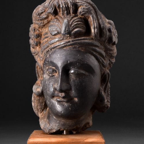 GANDHARAN DARK SCHIST HEAD OF BODHISATTVA 约。公元200-300年。 
这是一个深色片岩雕刻的菩萨头像，脸颊柔和圆润，&hellip;
