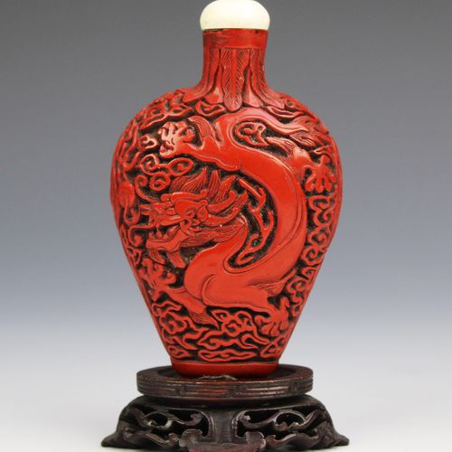 A carved cinnabar lacquer snuff bottle 朱砂雕漆鼻煙壺，19世紀，中國，壺身是扁圓形的，一側雕龍，另一側雕鳳凰，頸部雕有蕉&hellip;
