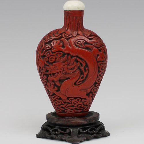 A carved cinnabar lacquer snuff bottle 朱砂雕漆鼻煙壺，19世紀，中國，壺身是扁圓形的，一側雕龍，另一側雕鳳凰，頸部雕有蕉&hellip;