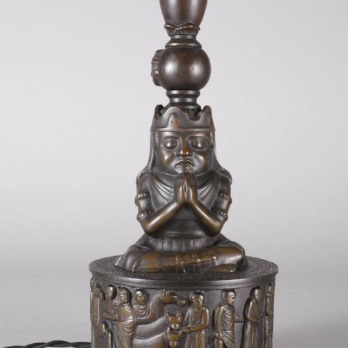 Null 
古铜色台灯
20世纪，青铜铸造，有深色的铜锈，圆形底座上有浮雕，周围有图画，上面有冥想姿势的坐姿，双火通电，纺织物覆盖的灯罩，高66厘米。