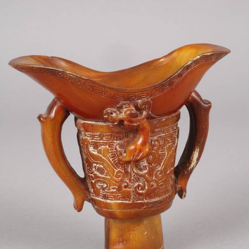 Null 
喇叭杯 
中国，约1900年，无署名，一个精心雕刻的琥珀色角的脚杯，有两个侧把手和一个摆动的嘴，四周装饰着古色古香的装饰和半塑料的龙，轻微的碰撞，高&hellip;