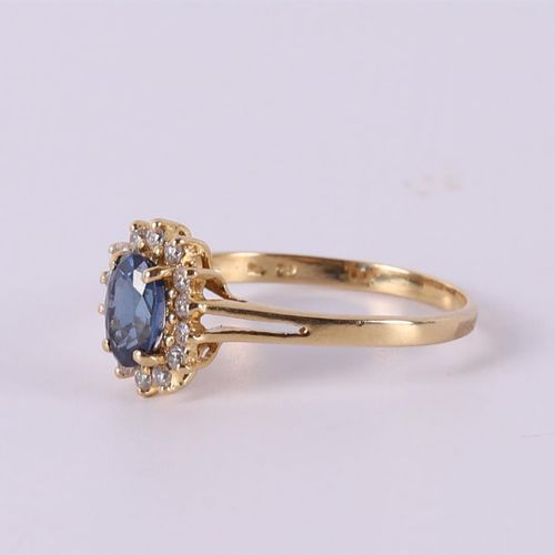 Null An 18 carat gold ring with an oval facet cut blue sapphire +14 diamonds