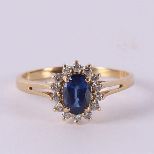 Null An 18 carat gold ring with an oval facet cut blue sapphire +14 diamonds